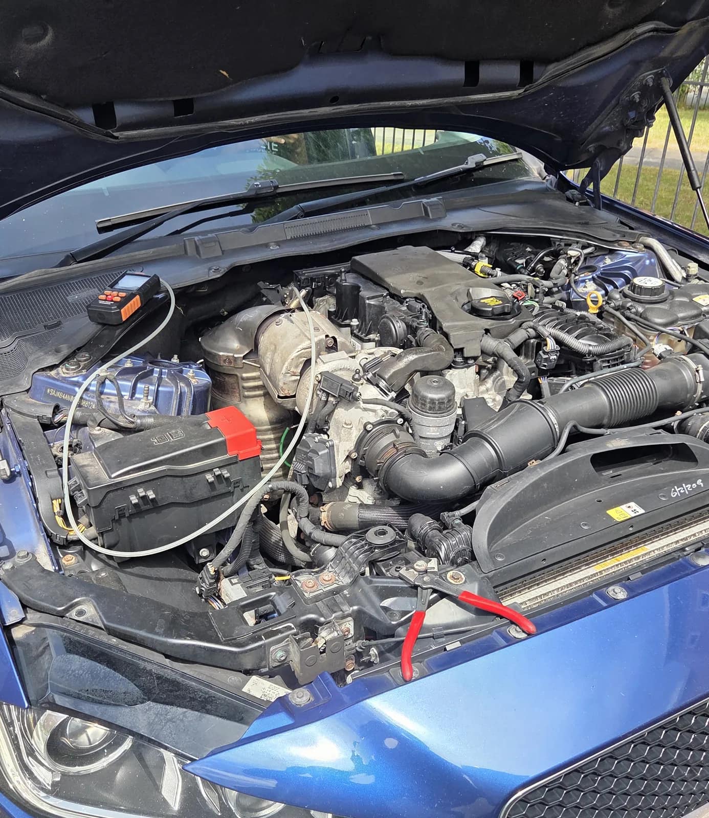 Blue Jaguar XE engine bay with the bonnet up during a job