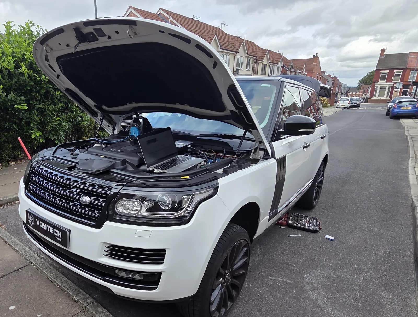 White Range Rover with the bonnet up and the kit connected on the street