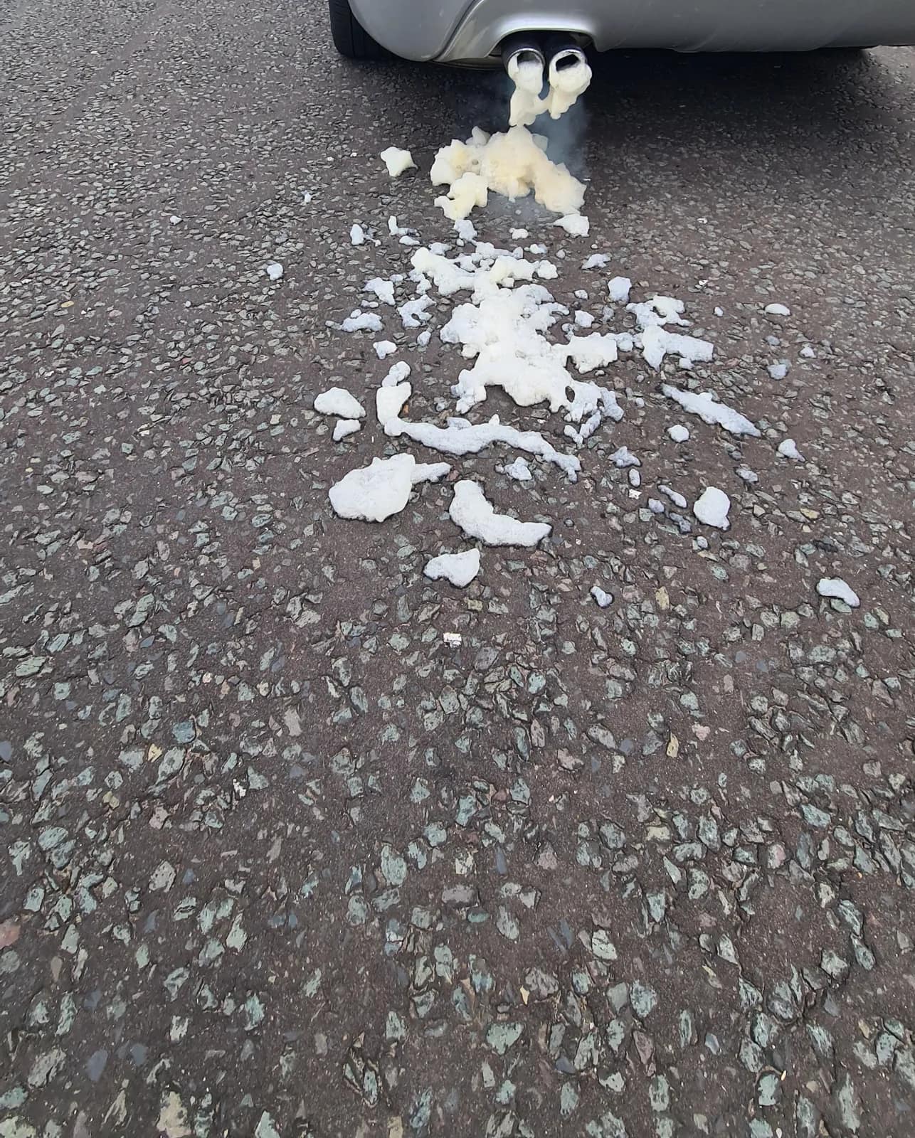 Foam flowing from the exhaust of a silver BMW 5 Series Touring during a DPF clean