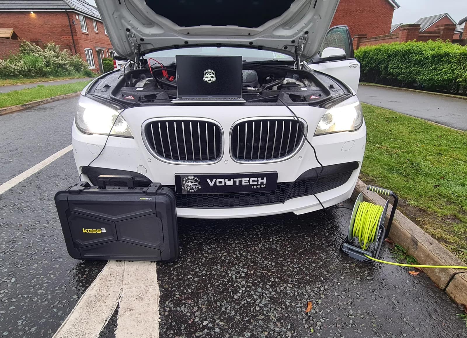 White BMW 730d with a laptop on the engine showing the Voytech logo and the tuning tool case in front