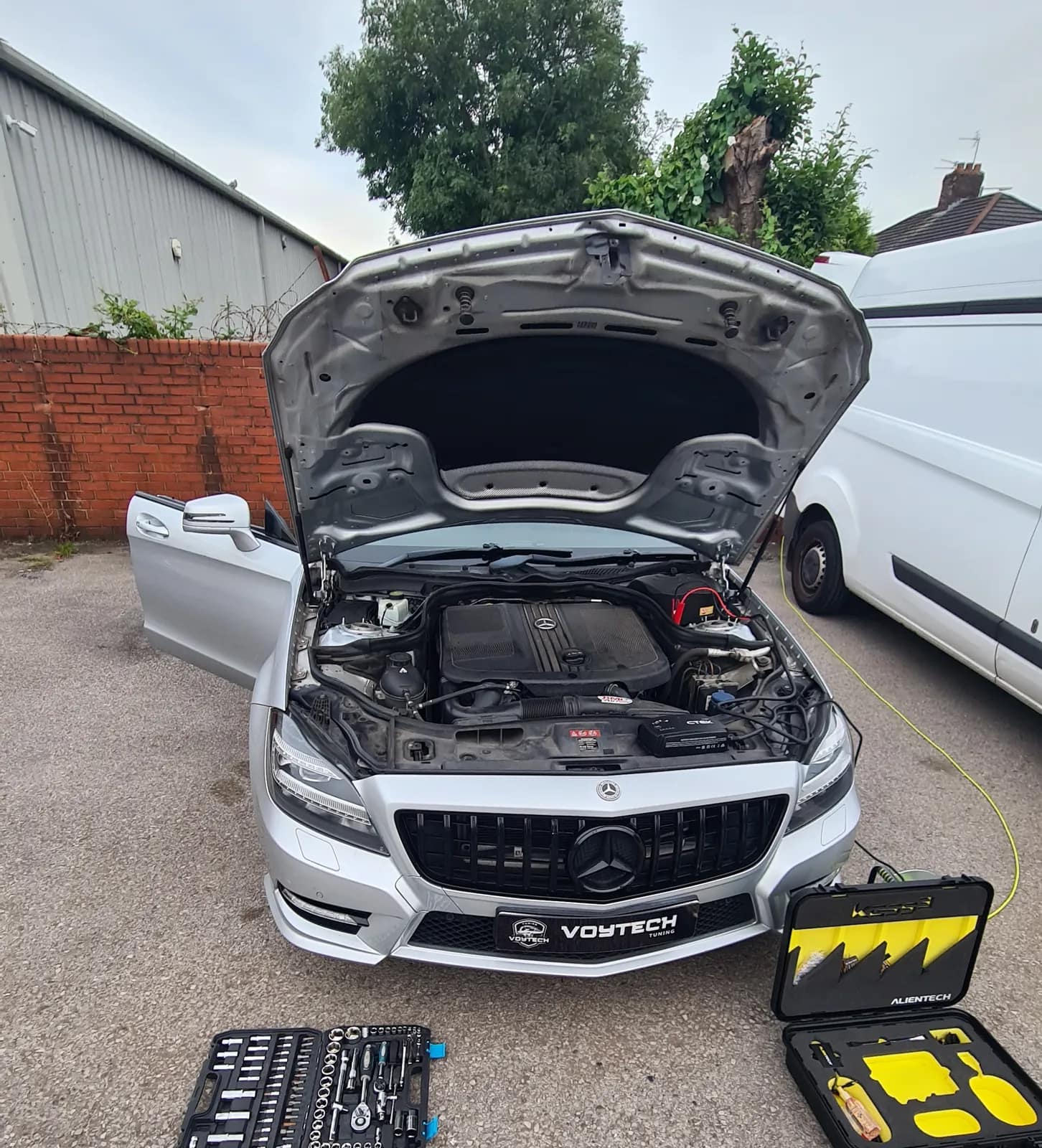 Silver Mercedes CLS Shooting Brake with the bonnet up and the tuning tool case in front