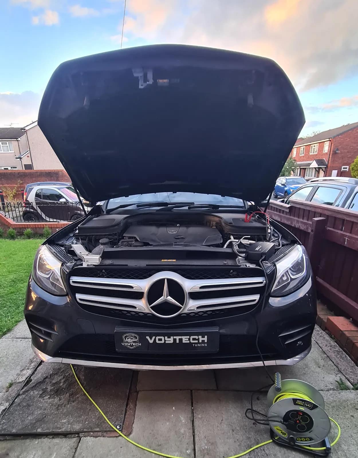 Black Mercedes GLC with the bonnet open and a VOYTECH plate at sunset