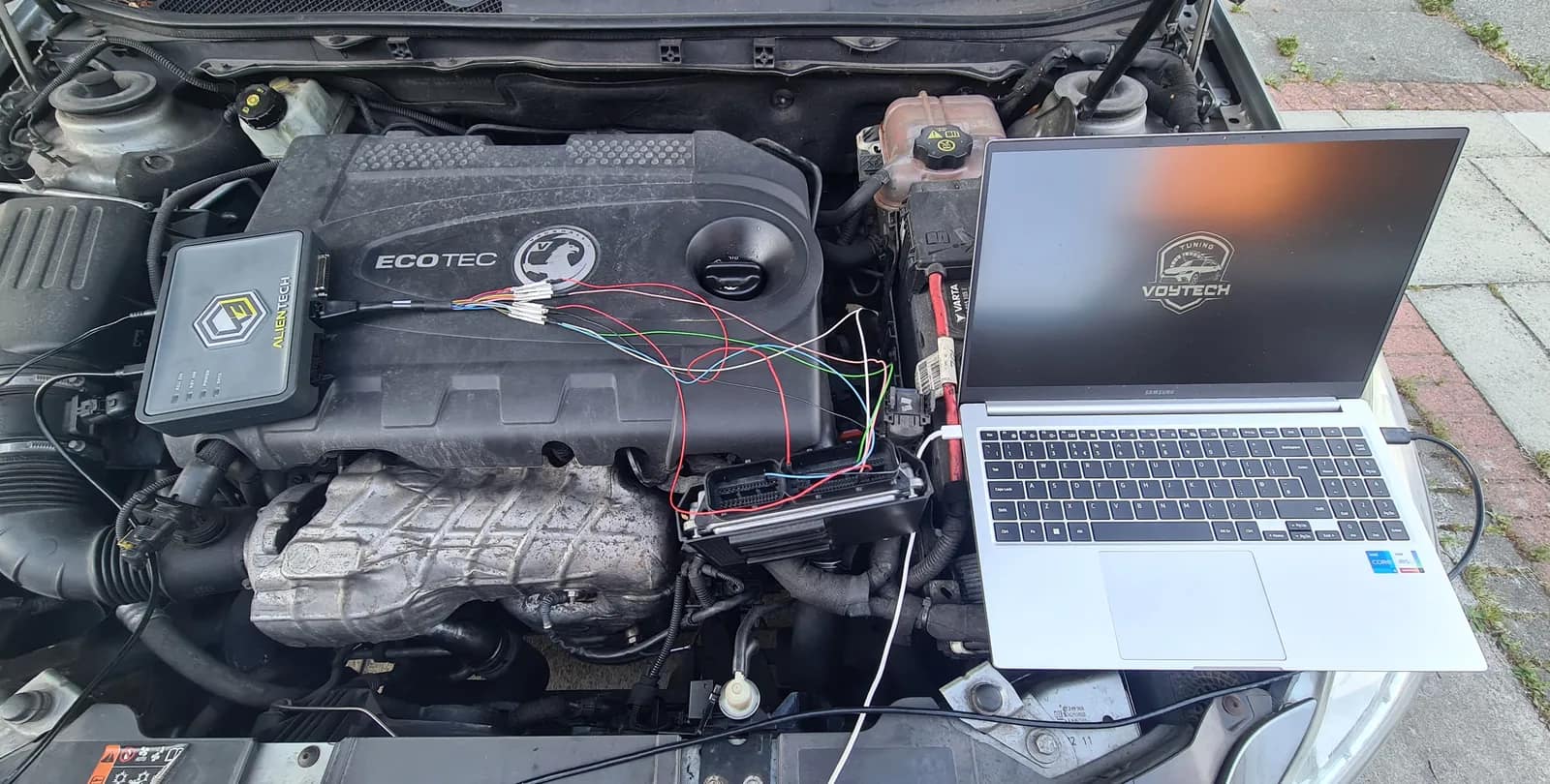 Laptop connected to a Vauxhall Insignia engine for ECU work on a driveway