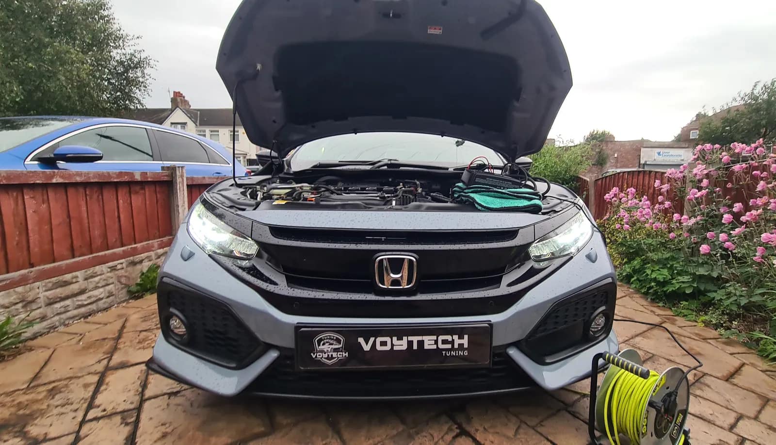 Grey Honda Civic with the bonnet open and a VOYTECH plate on a driveway