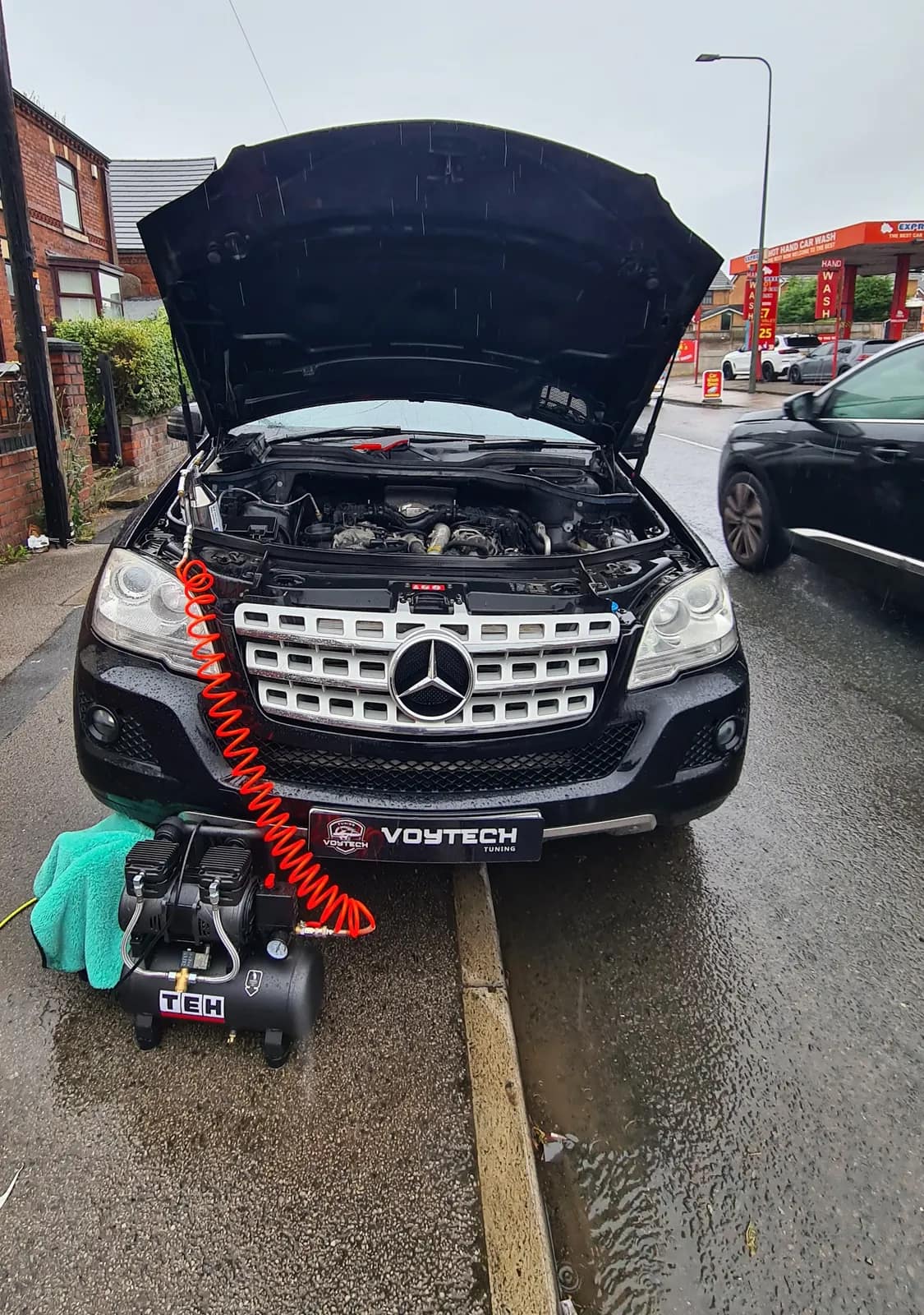 Black Mercedes ML with the bonnet open and the cleaning line fitted for a DPF clean on the street