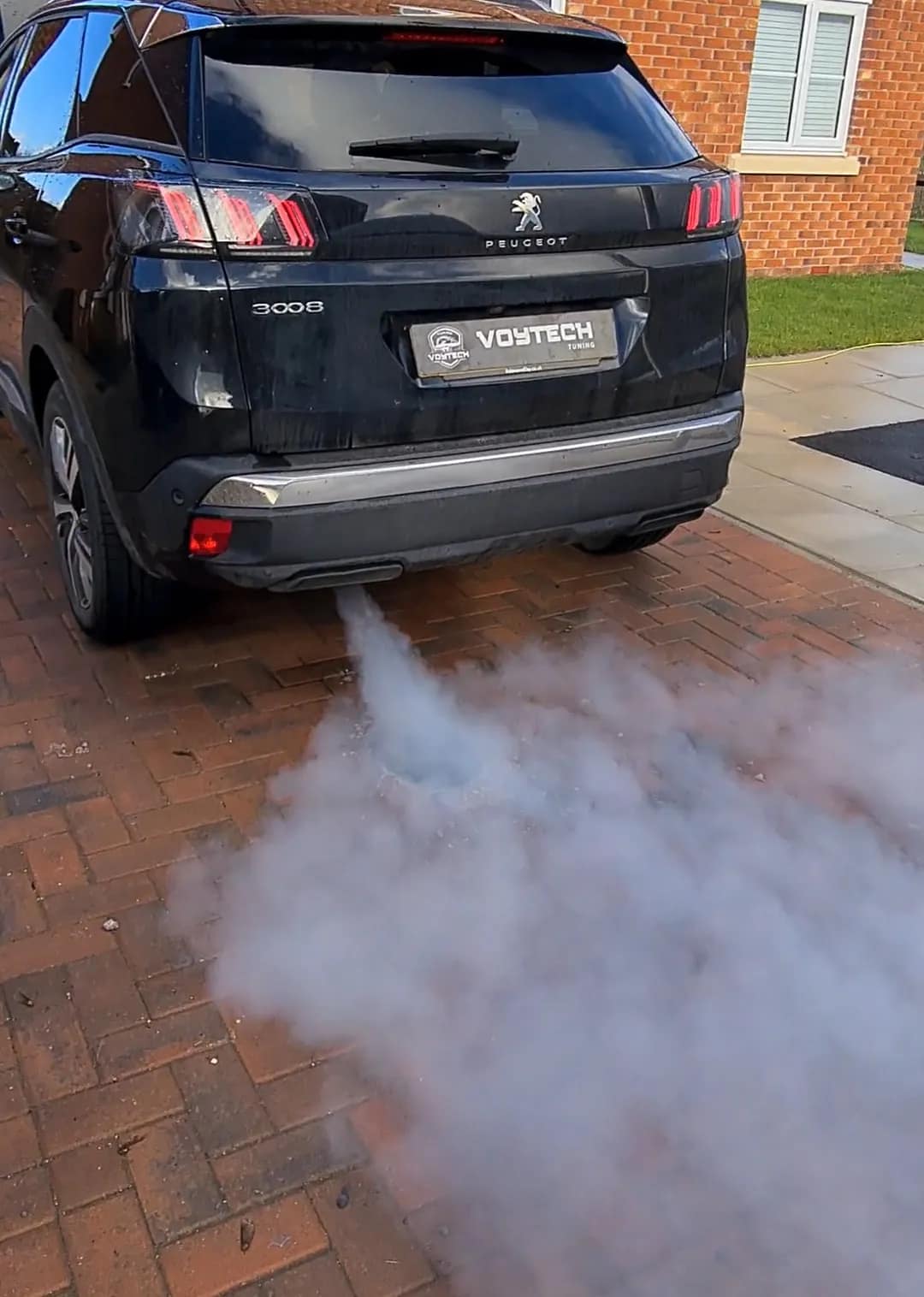 Black Peugeot 3008 blowing dense white smoke from the exhaust during a DPF clean