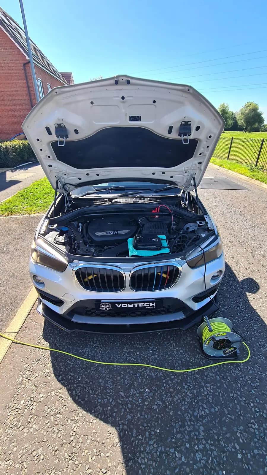 BMW with the bonnet up and the remapping kit connected on a driveway