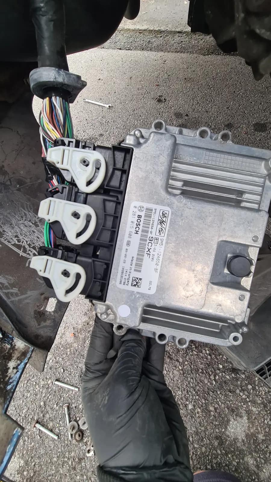 Engine control unit held in a gloved hand after removal